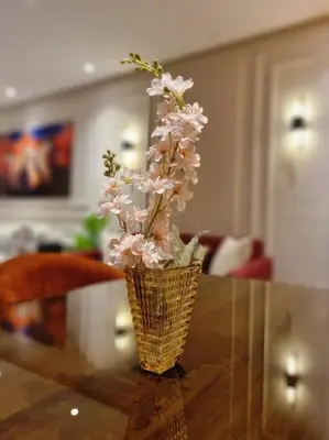 a vase with pink flowers sitting on a table at Appartement Central, vue Piscine-Golf, Lac et Montagne de L'atlas in Marrakech