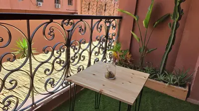 a wooden table on a balcony with a fence at Appart de luxe a gueliz a bon prix in Marrakech