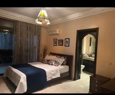 a bedroom with a bed and a bathroom with a mirror at Appartement impeccable en plein de centre ville in Marrakech