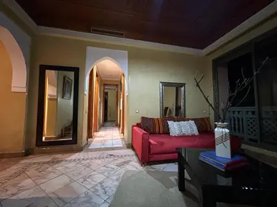 a living room with a red couch and a table at Appartement au palmeraie Marrakech in Marrakech
