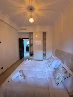 a large white bed in a room with a light at Appartement élégant près du stade in Marrakech