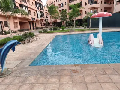 a swimming pool with a slide and a dolphin and an umbrella at Appartement élégant près du stade in Marrakech