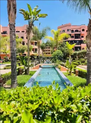 a view of a resort with a swimming pool and palm trees at Séjour Étoilé in Marrakech