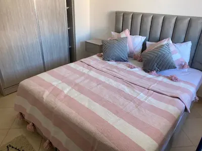 a bed with a pink and white blanket and pillows at Séjour Étoilé in Marrakech