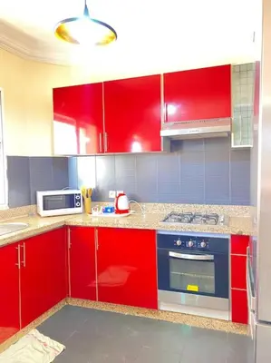 a kitchen with red cabinets and a stove top oven at Superbe Appartement avec Véranda et Terrasse in Marrakech