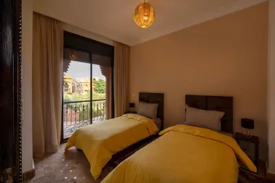 two beds in a room with a window at Villa Leya - Piscine chauffée in Marrakech