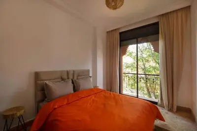 a bedroom with an orange bed and a large window at Villa Leya - Piscine chauffée in Marrakech