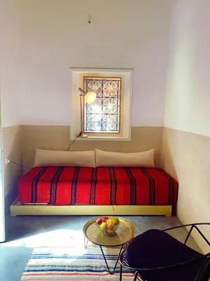 a bedroom with a bed with a table and a window at Maison traditionnelle au cœur de la Médina in Marrakech