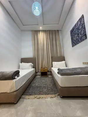 a bedroom with two beds and a rug at Square Appart in Marrakech