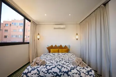 a bedroom with a bed and a large window at Élégant appartement avec terrasse au cœur Guéliz in Marrakech