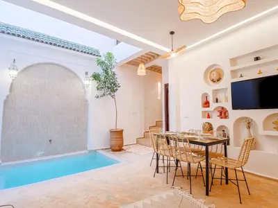 a living room with a table and a swimming pool at Riad Abati Piscine Privee avec Petit dejeuner et Terrasse in Marrakech