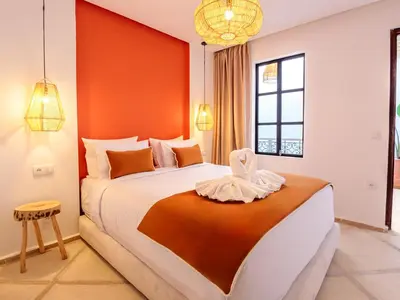 a bedroom with a large bed with an orange wall at Riad Abati Piscine Privee avec Petit dejeuner et Terrasse in Marrakech