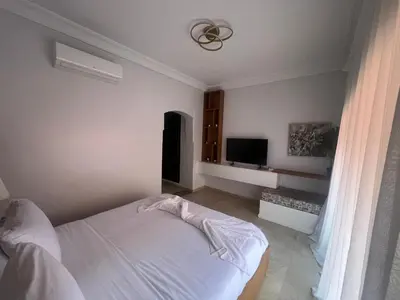 a white bedroom with a bed and a television at Bel Appartement meublé avec Piscine, l'hivernage à Marrakech in Marrakech