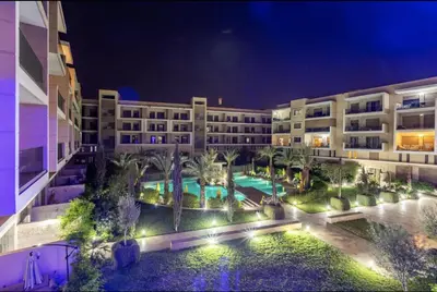 a large building with a pool and palm trees at night at Pearl Garden Studio Cosy Lux Elegant Sunny Terrace Piscine in Marrakech