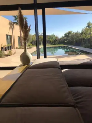a living room with a couch and a palm tree at Villa M avec Piscine Chauffée in Marrakech