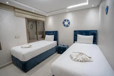 two beds in a small room with a window at Appartement cosy au cœur de Semlalia in Marrakech