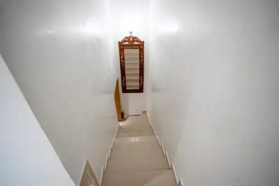 a staircase leading up to a white wall with a clock at Appartement cosy au cœur de Semlalia in Marrakech