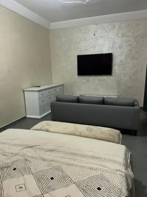 a bedroom with a couch and a tv on the wall at Appt 10min pied jardin Majorelle in Marrakech