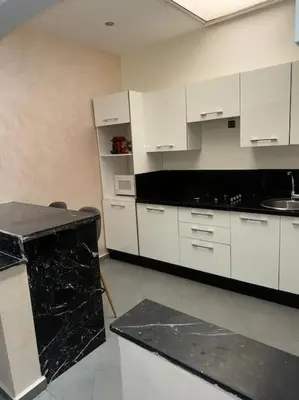 a kitchen with white cabinets and a black counter top at Appt 10min pied jardin Majorelle in Marrakech