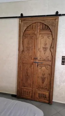 a large wooden door in a room with a bed at Appt 10min pied jardin Majorelle in Marrakech