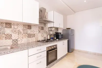 a kitchen with white cabinets and a stainless steel refrigerator at Luxury and Healthy designed Apartment with pool in Marrakech