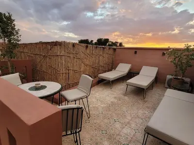 a patio with a table and chairs and a sunset at Dar Amazigh mit 3 Schlafzimmern in Marrakech
