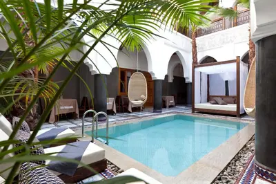 a pool in a hotel with a palm tree at Hotel & Spa Riad El Walaa in Marrakech