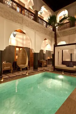 a large swimming pool in a hotel with a palm tree at Hotel & Spa Riad El Walaa in Marrakech