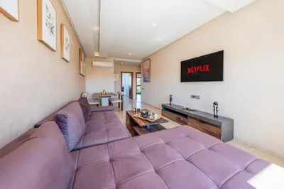 a living room with a purple couch and a tv at Cute And Modern Appart In Prestigia in Marrakech