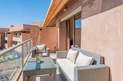 a patio with a couch and a table on a balcony at Cute And Modern Appart In Prestigia in Marrakech