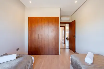 a bedroom with two beds and a wooden door at Cute And Modern Appart In Prestigia in Marrakech