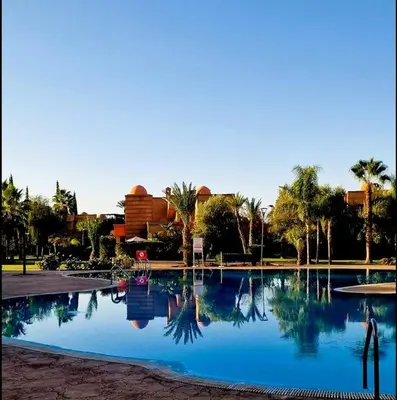 a large swimming pool with palm trees and a building at Dar Ou Bahssou in Marrakech
