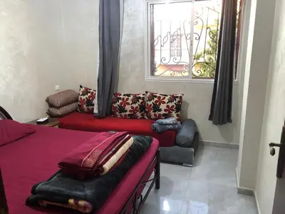 a bedroom with a bed and a couch and a window at AC Family apartment steps away from everything in Marrakech
