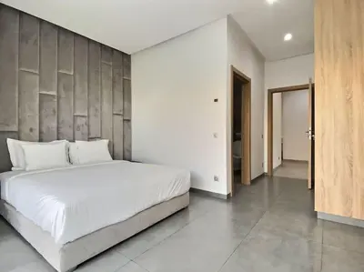 a bedroom with a white bed and a wooden wall at Villa Léna détente en famille ! in Marrakech