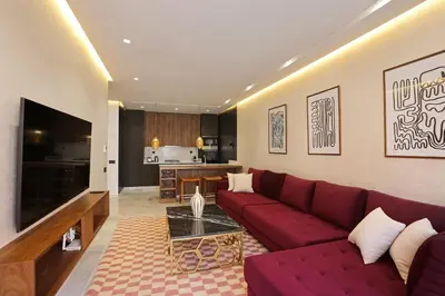 a living room with a red couch and a kitchen at Brand New and Stylish appart hotel Best location in Marrakech