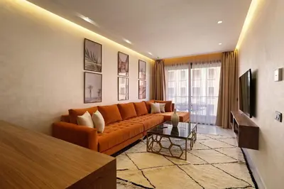 a living room with an orange couch and a television at Brand New and Stylish appart hotel Best location in Marrakech