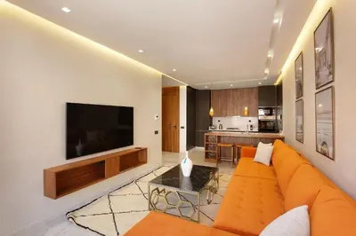a living room with an orange couch and a television at Brand New and Stylish appart hotel Best location in Marrakech