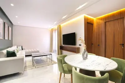 a living room with a table and green chairs at Brand New and Stylish appart hotel Best location in Marrakech