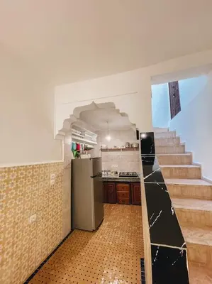 a kitchen with a refrigerator and stairs in a room at Riad Dar Habiba 120m2 in der Medina mit Terrasse in Marrakech