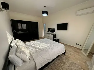 a bedroom with a white bed and a television at Luxury Appartement with Pool in Marrakech
