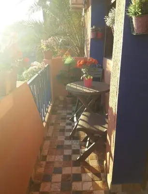 a small table on a balcony with potted plants at Centre ville Majorelle avec Parking gratuit in Marrakech