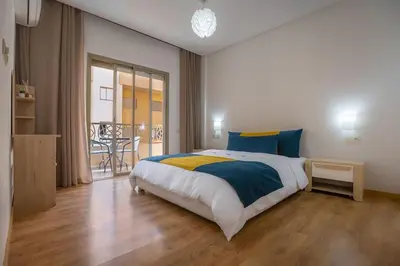 a bedroom with a large bed and a balcony at Charming two bedrooms Flat with Pool and Parking in Marrakech