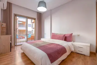 a white bedroom with a large bed and a window at Spacious 2 BR FLAT with Wi-Fi, Pool and Parking in Marrakech