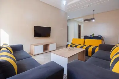 a living room with blue and yellow couches and a tv at Spacious 2 BR FLAT with Wi-Fi, Pool and Parking in Marrakech