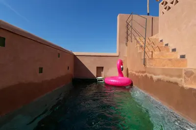 a swimming pool with a pink swan in the water at Riad & Spa, Doum Collection in Marrakech
