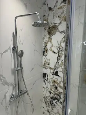 a shower with a glass door with a microphone in a bathroom at Appartement Cosy in Marrakech