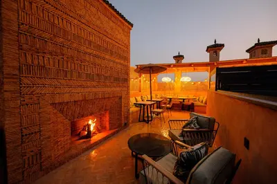 an outdoor patio with a fireplace and tables and chairs at Door Janna in Marrakech