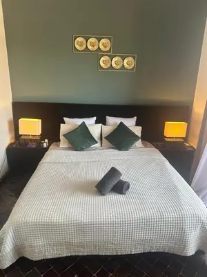 a bedroom with a large white bed with green pillows at Magnifique appartement 3 chambres et piscine de standing in Marrakech
