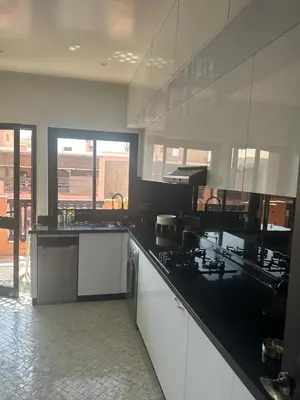 a kitchen with white cabinets and black counter tops at Magnifique appartement 3 chambres et piscine de standing in Marrakech