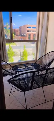 a table and chairs in front of a window at Un élégant appartement à louer à Marrakech avec deux piscines et une situation en centre ville in Marrakech
